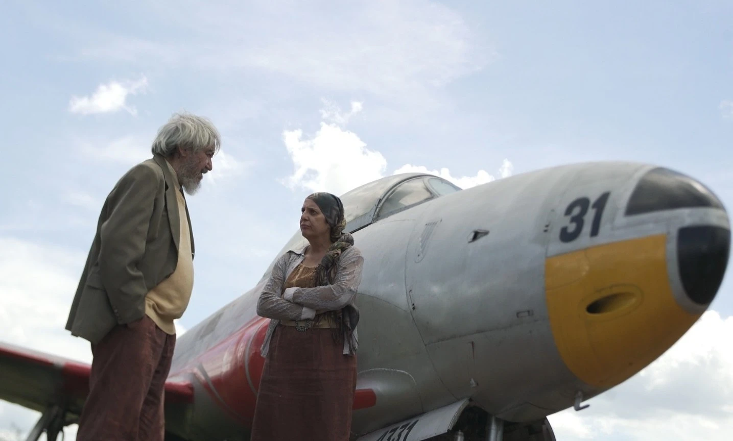 Cena de Ressonâncias Temporais com dois personagens ao lado de um avião.